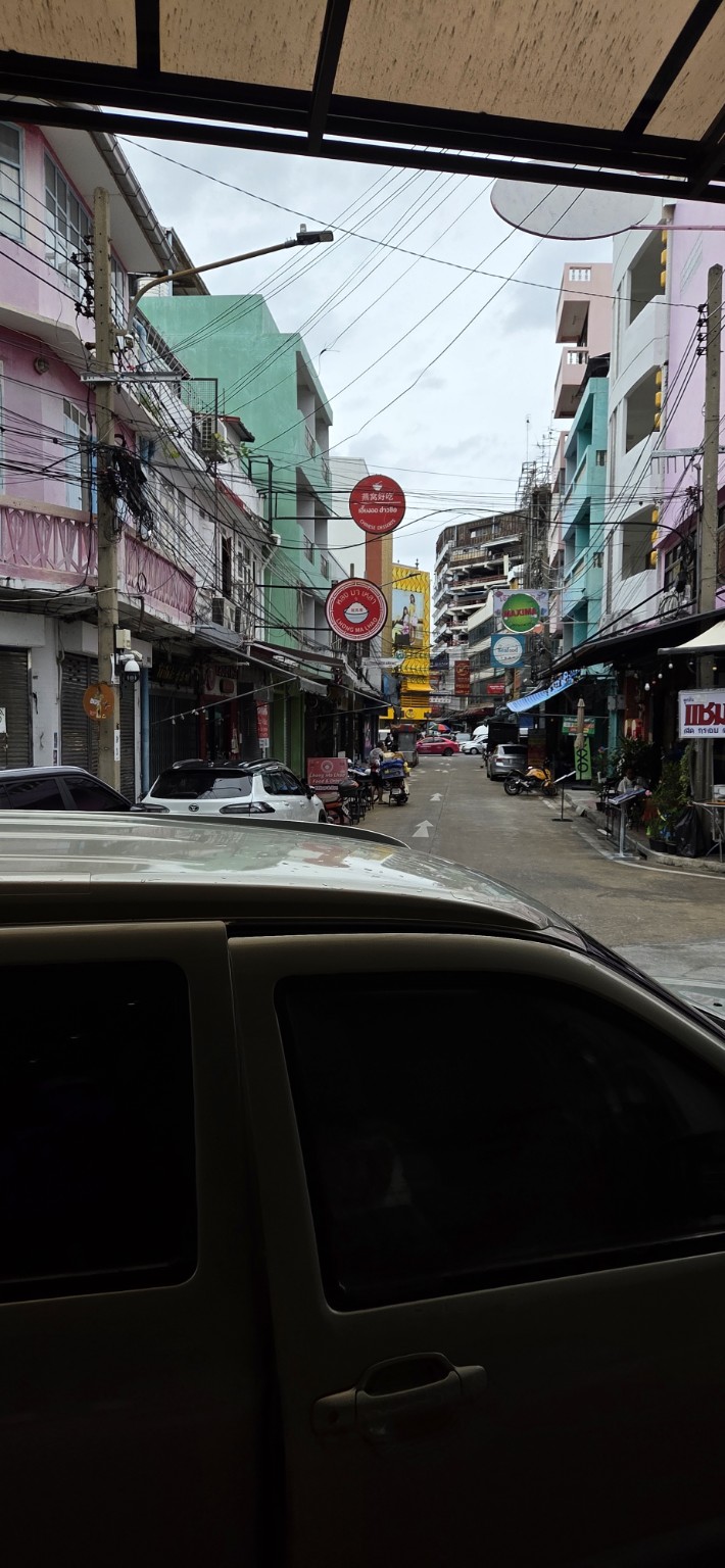 A colorful Bangkok street beneath a web of utility lines
