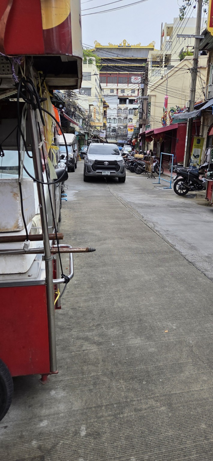 Narrow Bangkok lane with a food cart and motorcycles