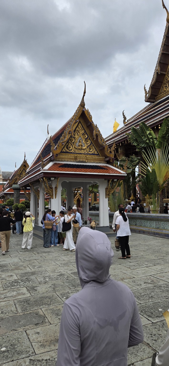 A small ornate pavilion in a busy Grand Palace courtyard