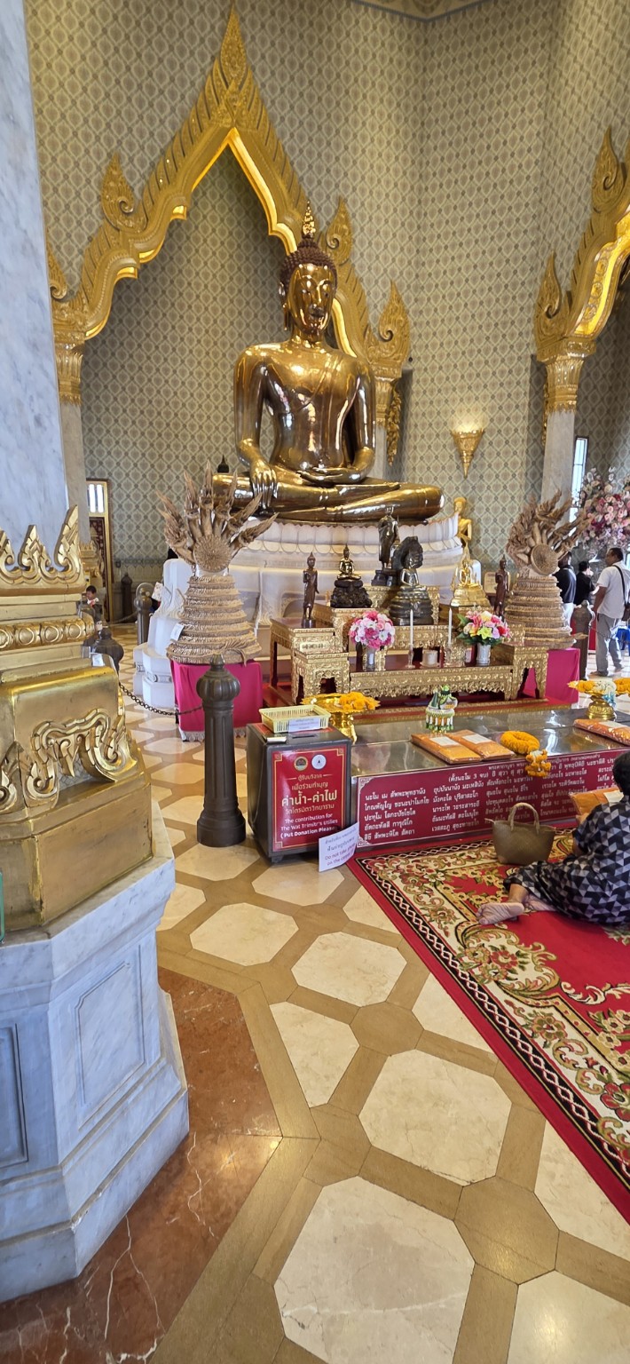 Golden seated Buddha inside an ornate Bangkok temple